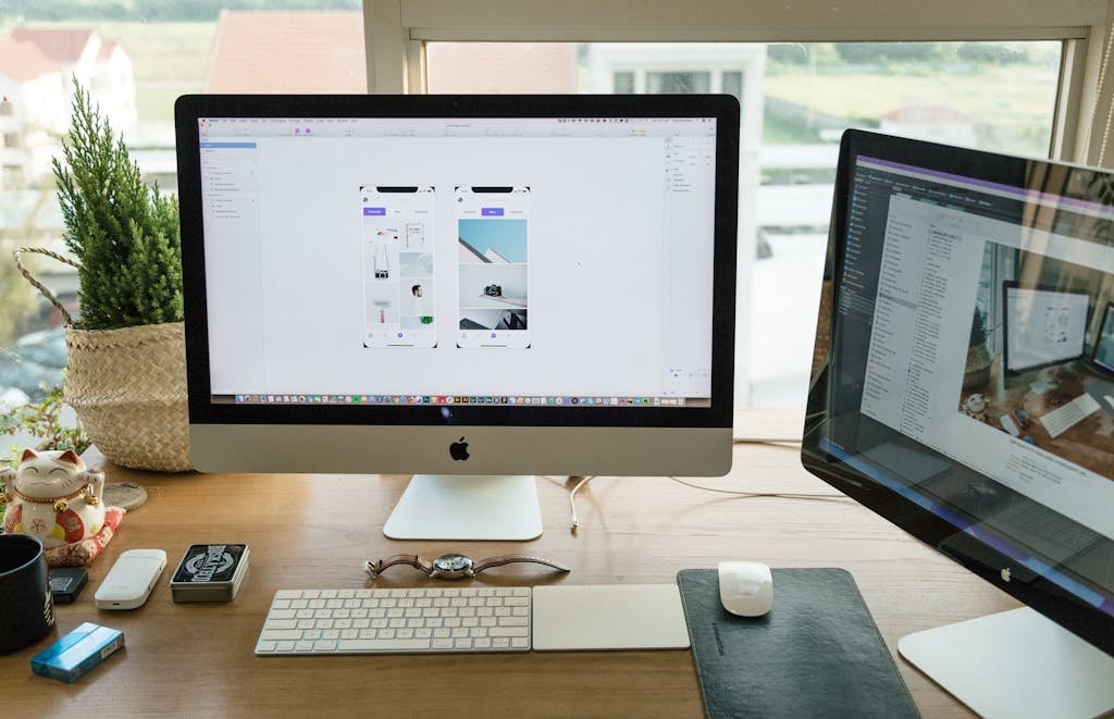 A well-organized modern office setup featuring Apple iMac and multiple monitors in a bright workspace.